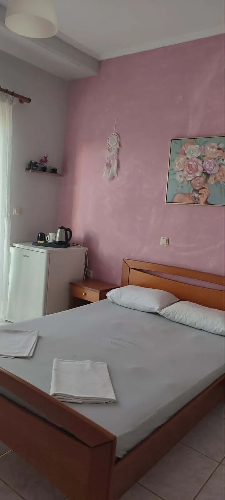 Double room with pink wall and wooden bed